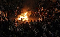 Picture that shows protesters blocking a road and holding national flags as they gather around a bonfire during a rally against the Israeli government's judicial reform in Tel Aviv, Israel, on March 27, 2023