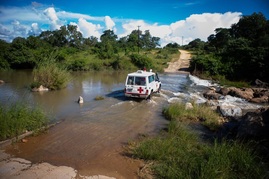 A vehicle crosses a flooded road in a remote area.
