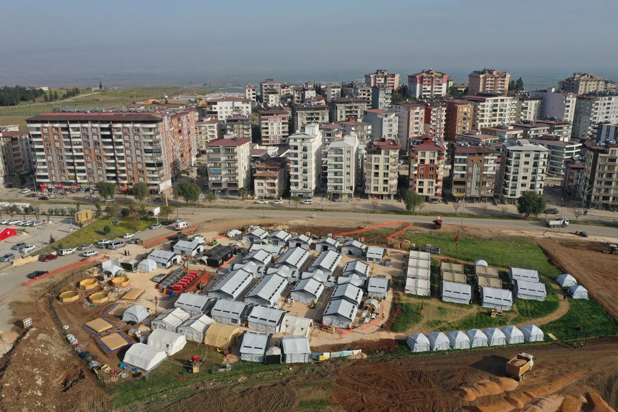 An aerial view of dozens of tents set up beside residential buildings