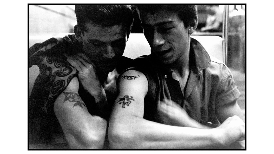 A photo of two young men with tattoos on their arm