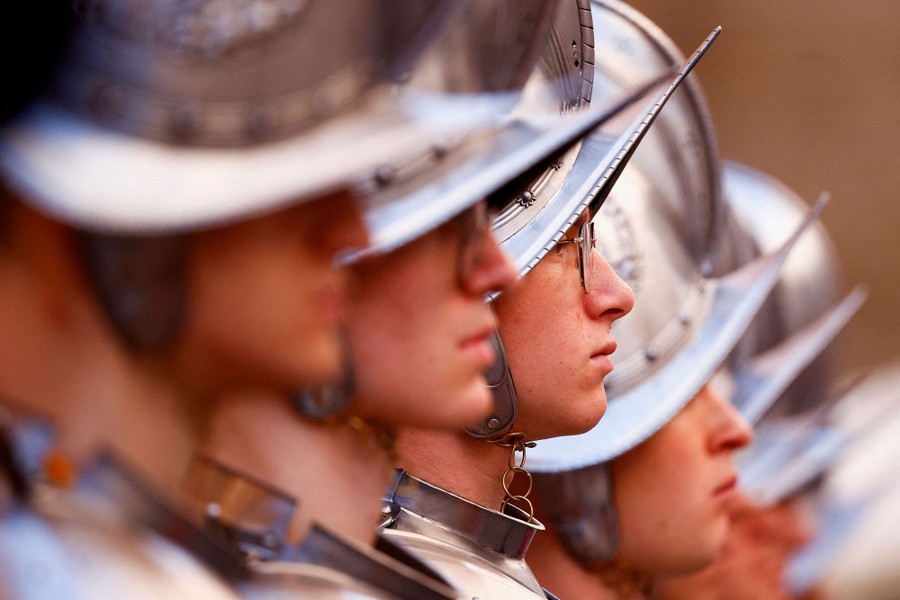 A line of Swiss Guard trainees wearing traditional armored helmets, seen from the side