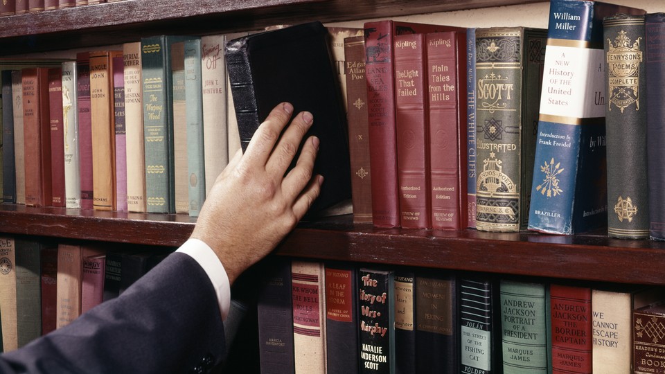 A hand pulling a book from a shelf