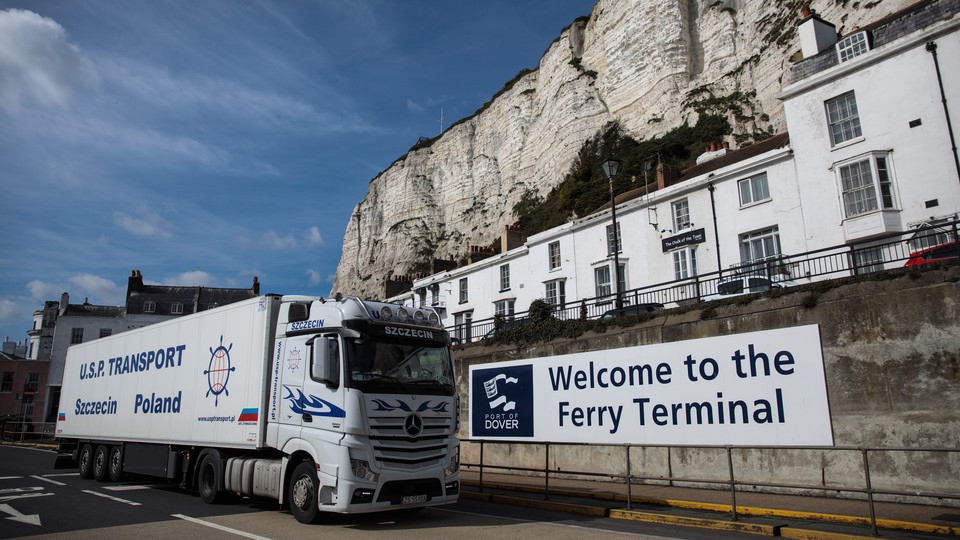 A truck passes a cliff and a sign that says "Welcome to the Ferry Terminal."