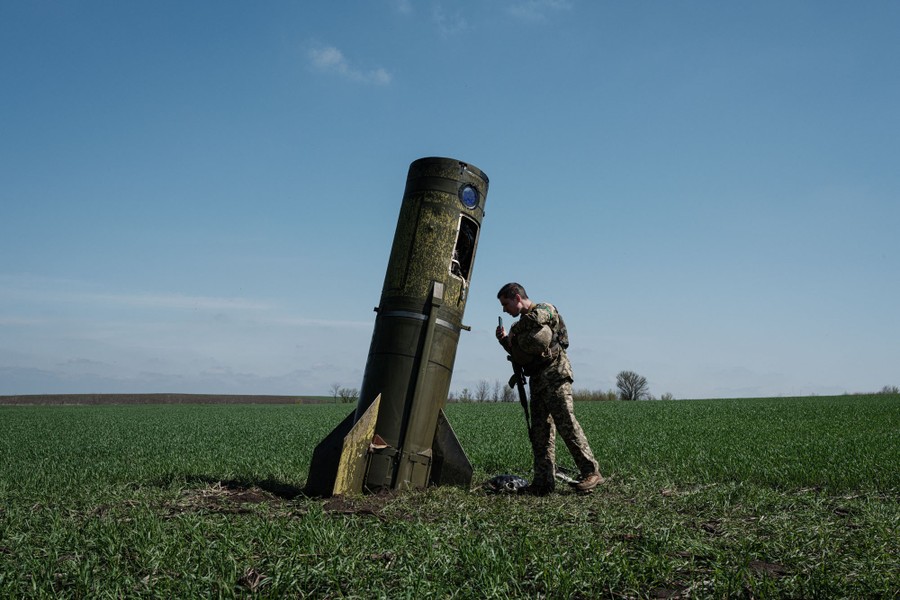 A soldier looks at the remains of part of a missile that dropped into a farm field.
