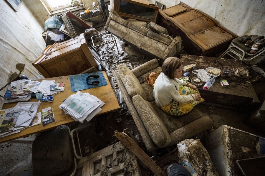 A woman sits in her muddy, destroyed apartment.