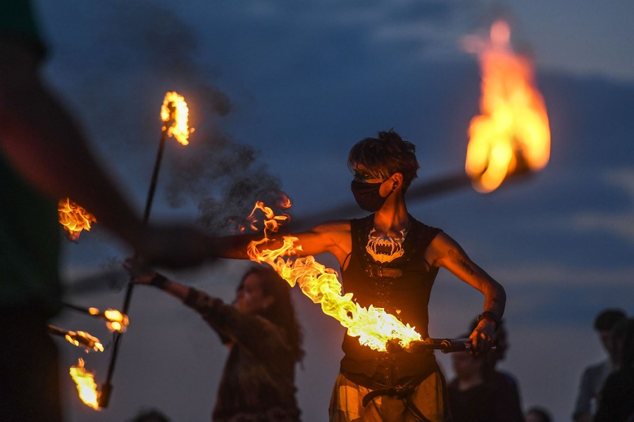 People dance while holding lit torches and poles.
