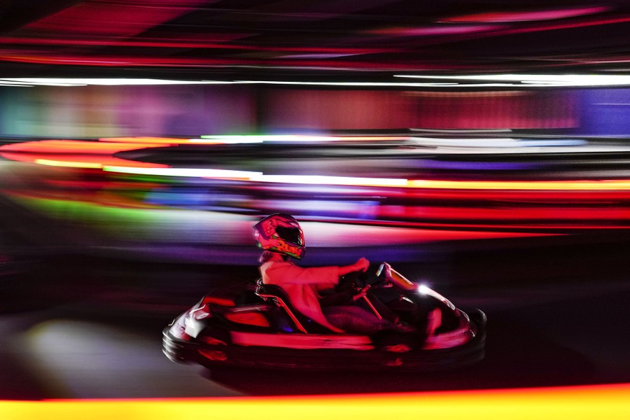 A person drives a go-kart surrounded by colorful lights.
