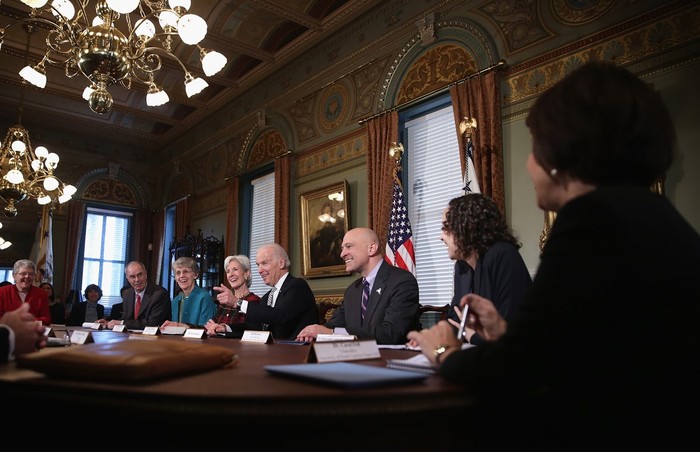 Joe Biden is seen sitting at a table with college presidents and others. 