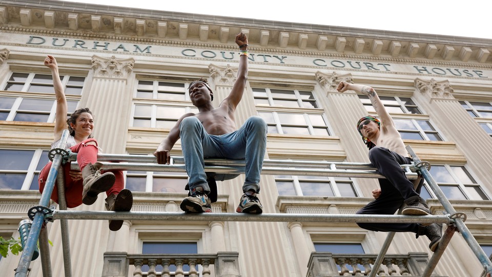 Protestors sit on scaffolding outside the old Durham County courthouse.