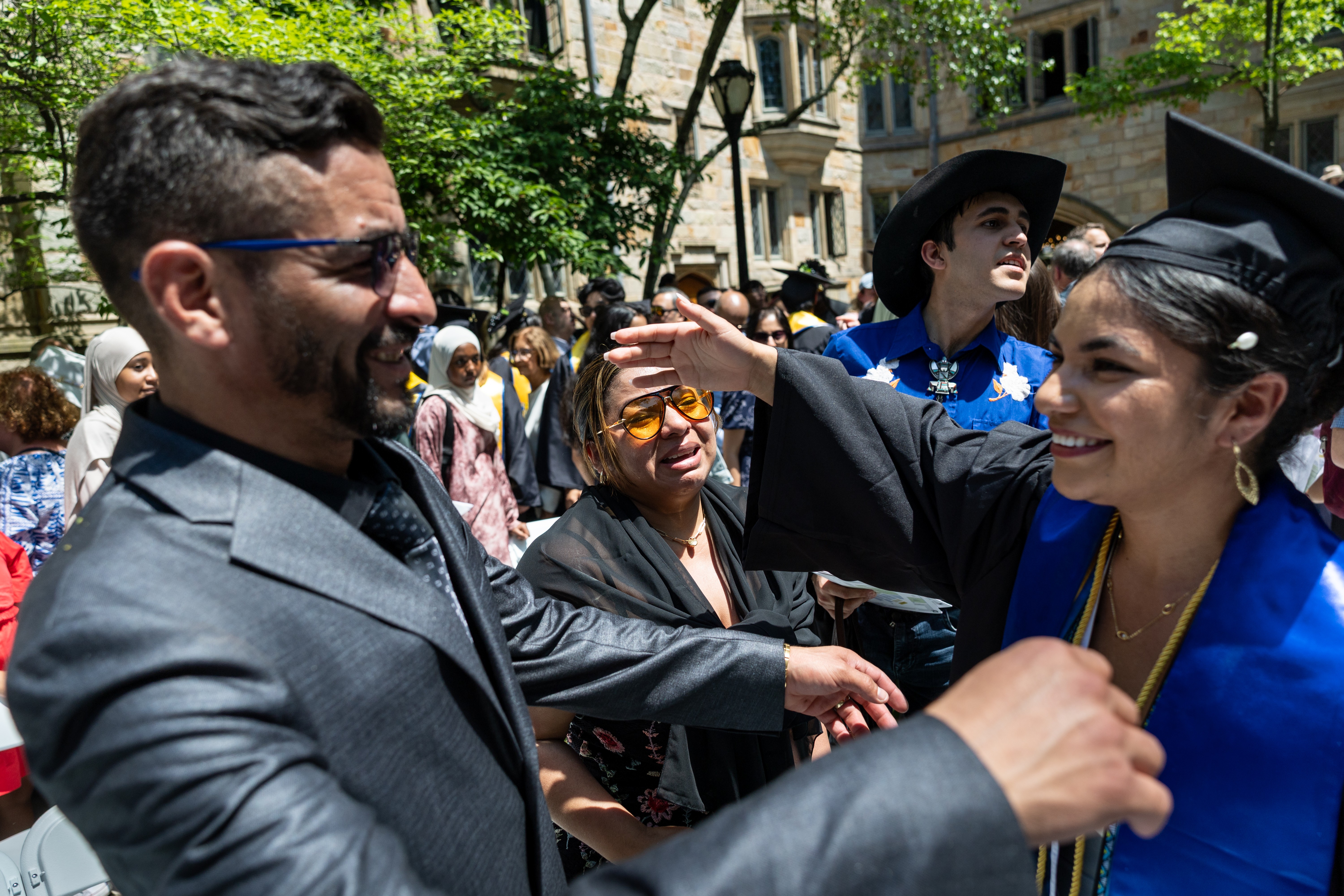 Parents at a graduation ceremony embrace their graduating daughter.