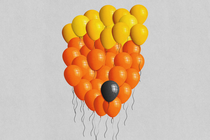 A cluster of yellow and orange balloons configured to look like Donald Trump, with one black balloon floating among them.