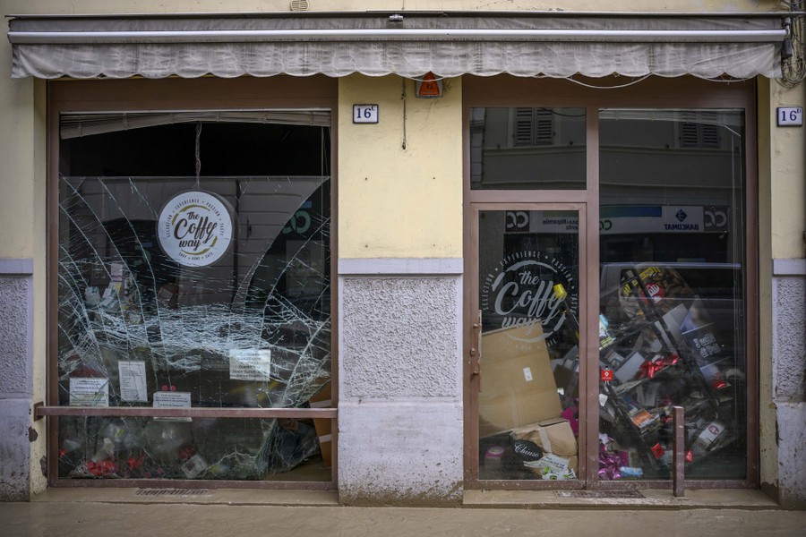A storefront with broken glass and flood damage inside