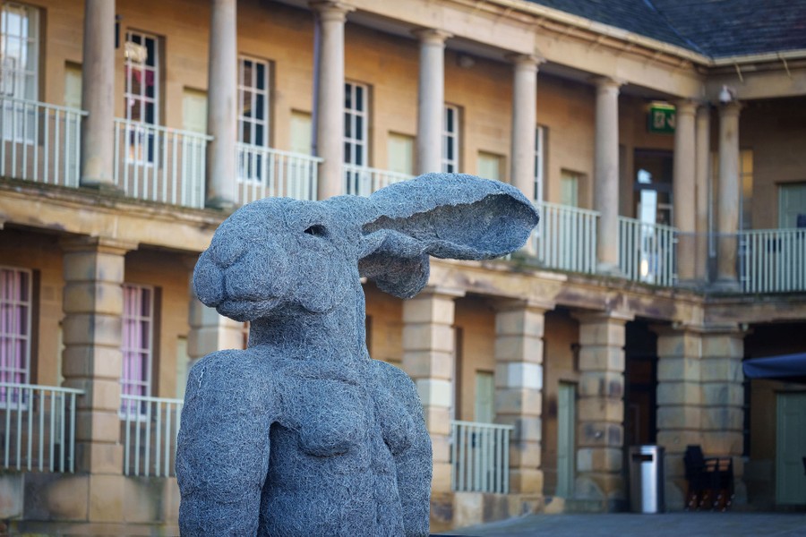 A large sculpture of an anthropomorphized rabbit stands in a courtyard.