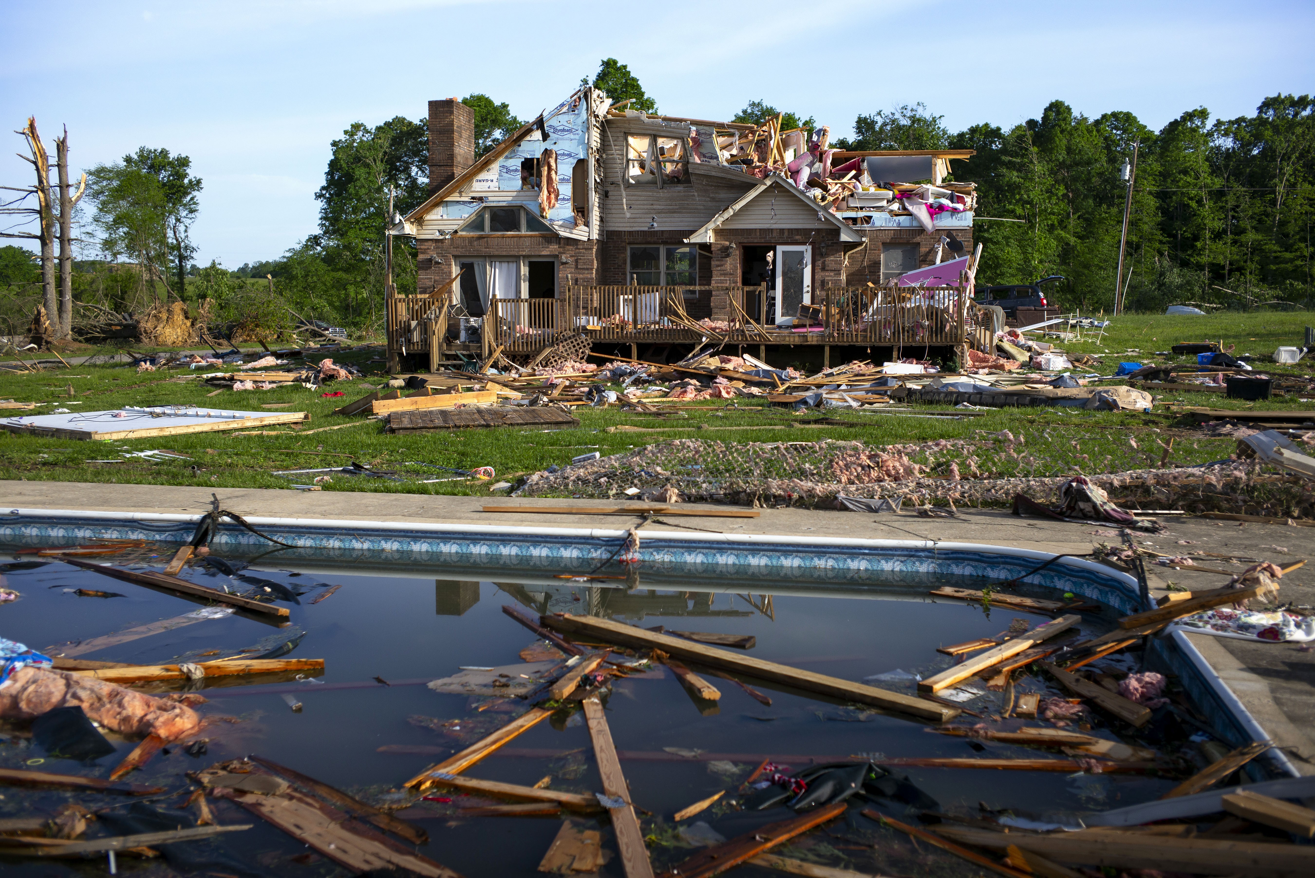 Debris floats in a pool near a severely storm-damaged house.