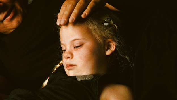 parent with hand on head of young girl