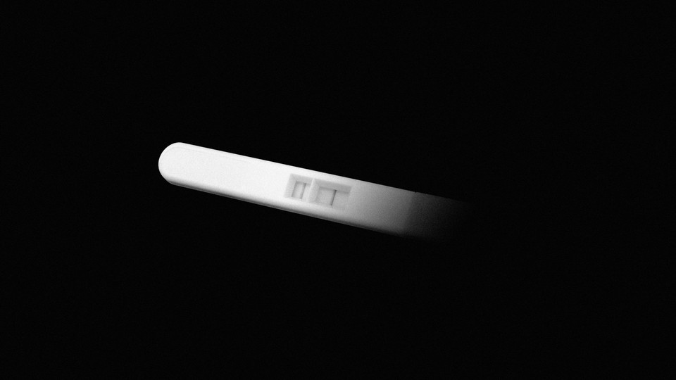 A pregnancy test coming out of the shadow of a black background