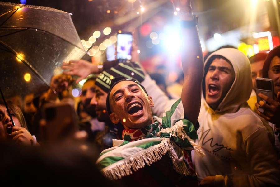 Soccer fans celebrate and cheer in a street.