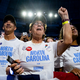 Delegates from North Carolina stand in a crowd, one raising her fist, at the Democratic National Convention