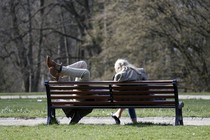 One person sitting and the other lounging with feet up on a bench
