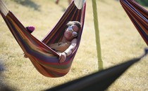 A person wearing sunglasses lies in a hammock.