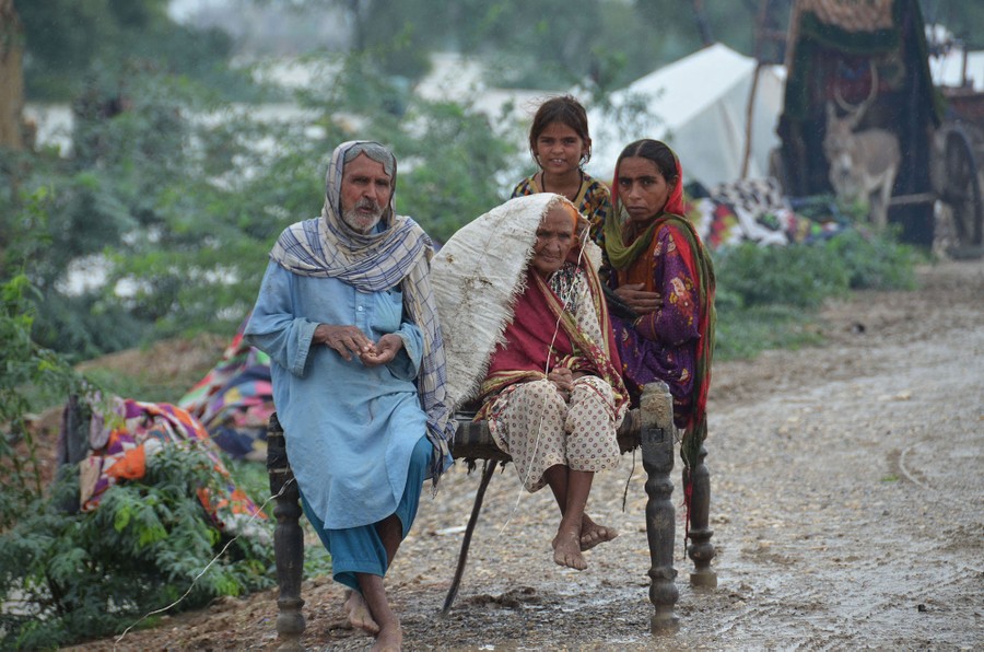 Four family members sit together on a piece of furniture set outside.