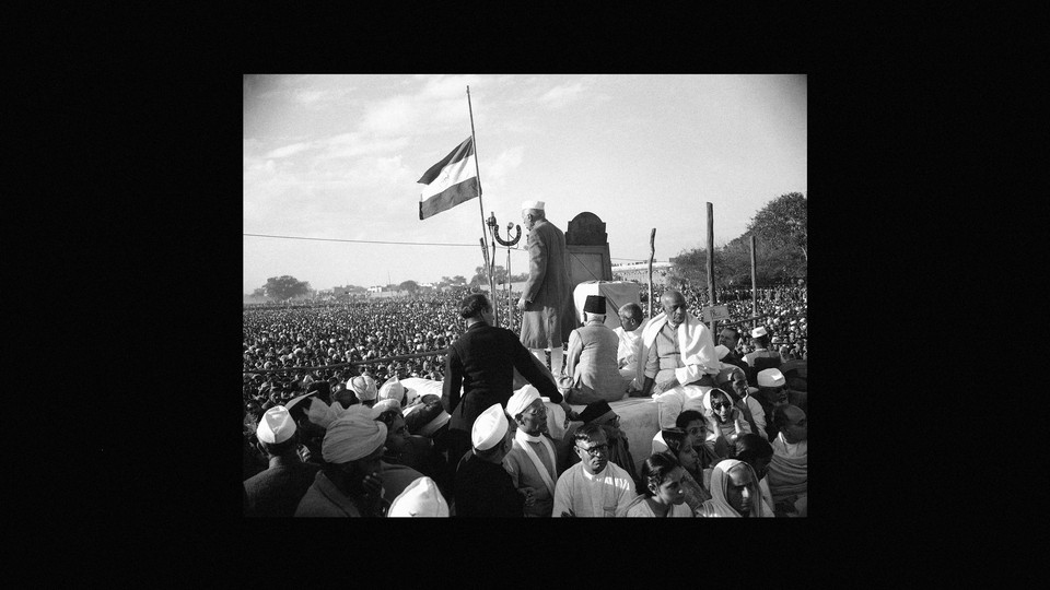 Jawaharlal Nehru si rivolge a una folla con la bandiera indiana a mezz'asta.