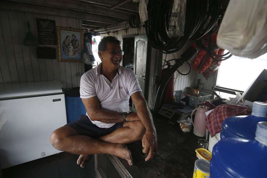 A person sits among belongings on a dredging barge.