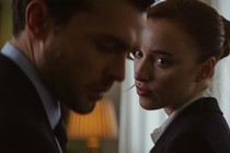 a brunette woman looks at a man who is blurry in the foreground