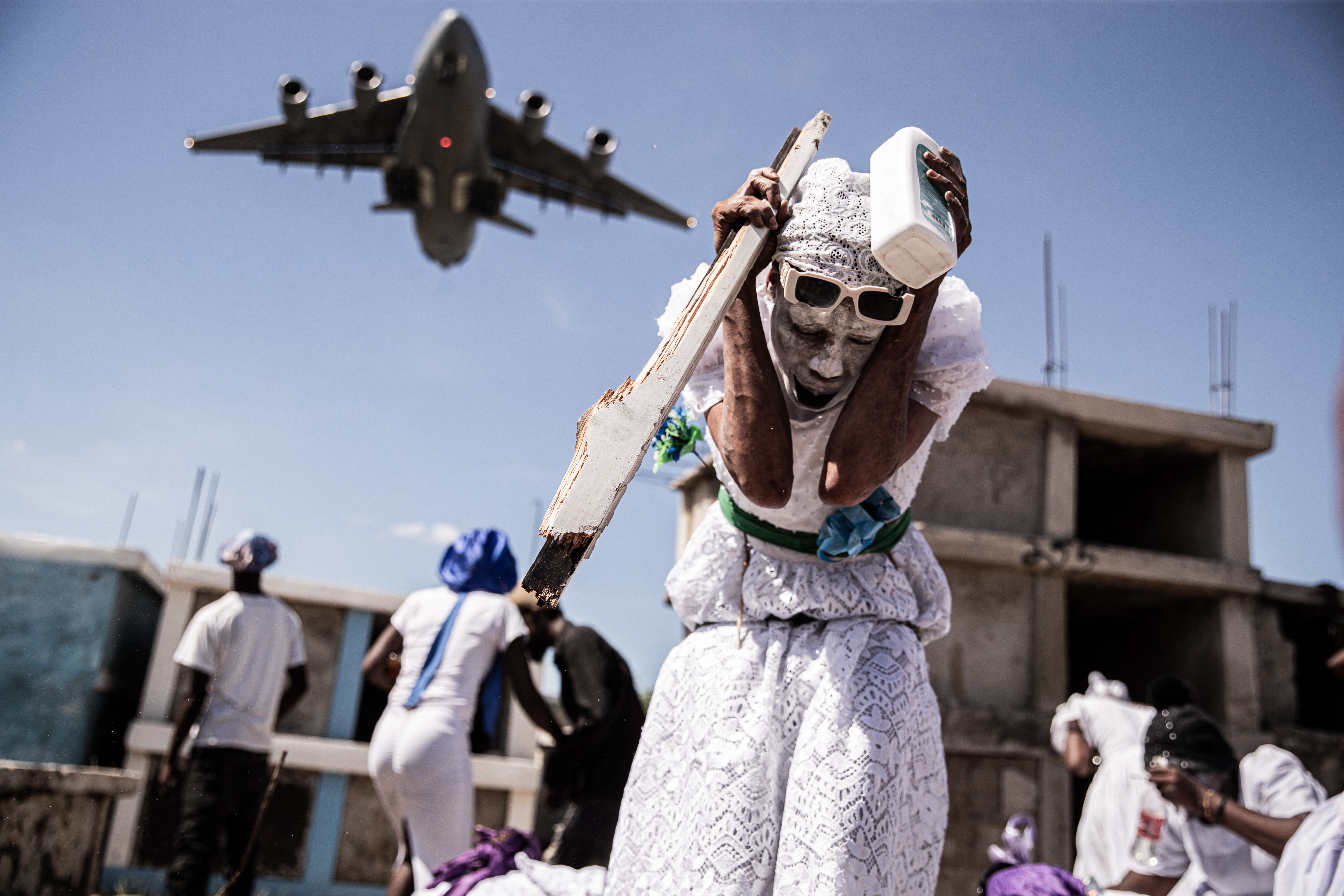 A woman reacts as a low-flying aircraft passes over, during a celebration in a cemetery.