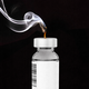 A vial of medicine with a smoking candlewick on top