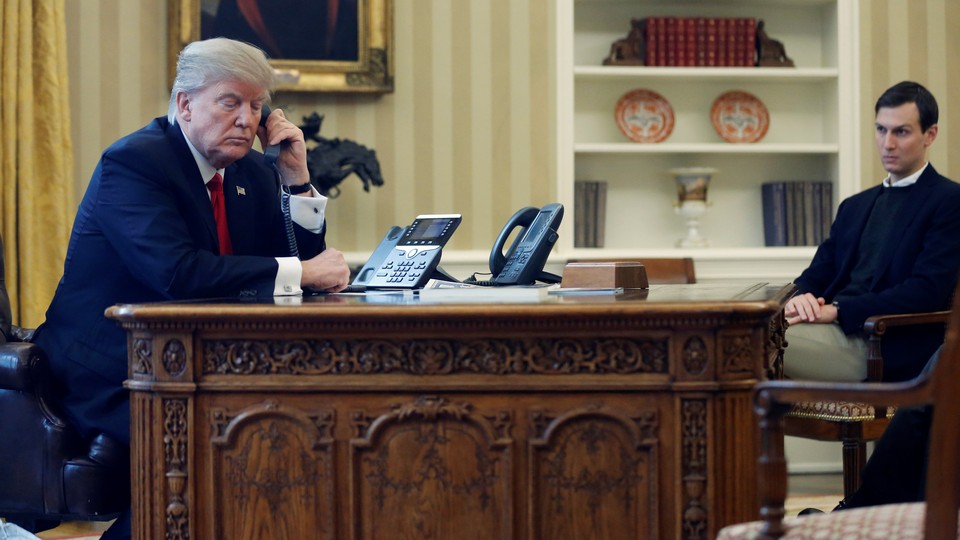 Donald Trump speaks on the phone as Jared Kushner looks on.