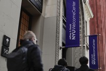 Students walk along a street with NYU banners