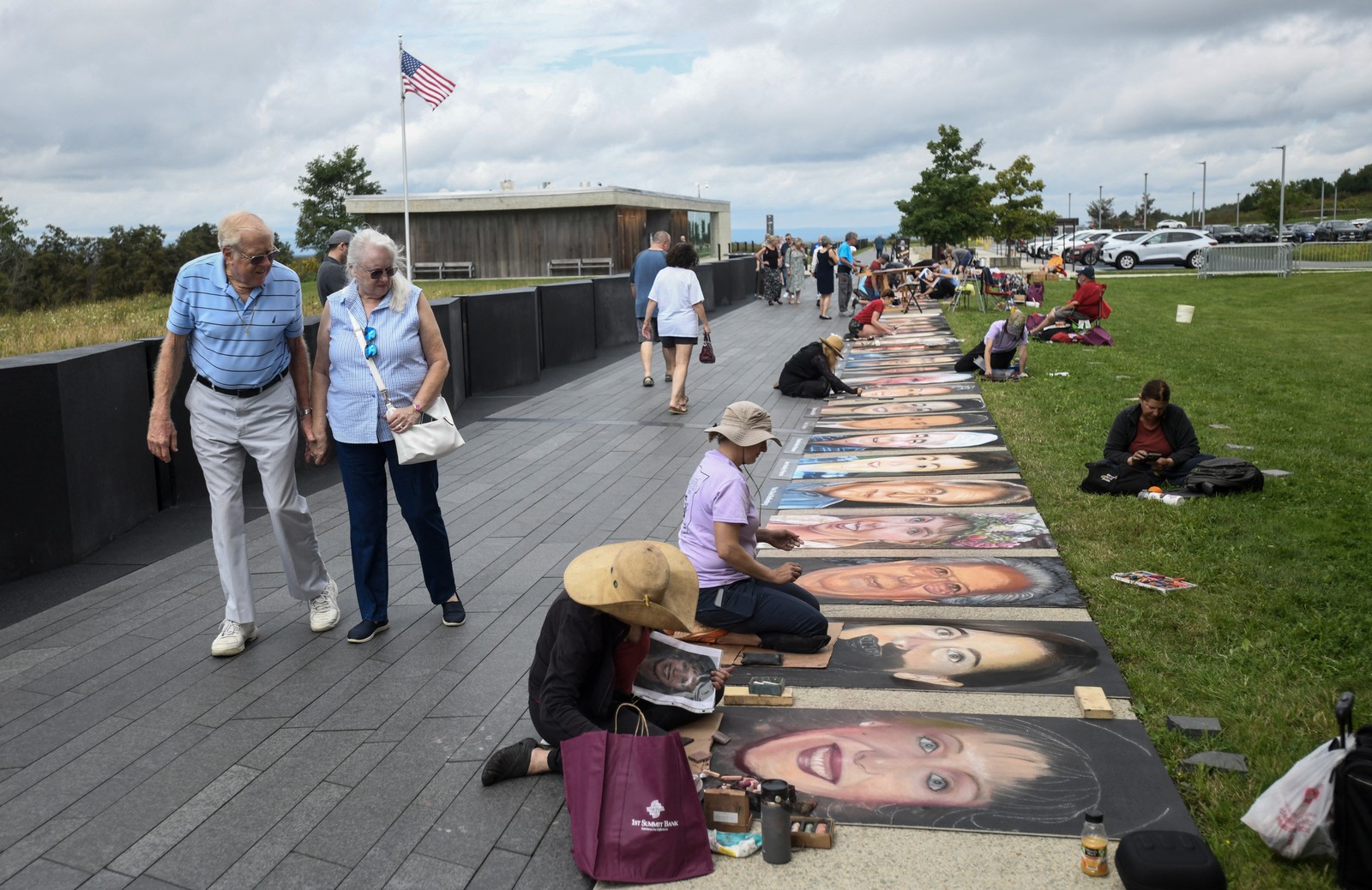 People watch as about 20 artists draw chalk portraits of the passengers and crew of Flight 93, alongside a pathway.