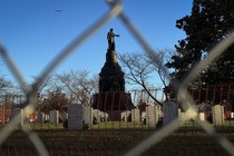 A photo of the Confederate Memorial in Arlington Cemetery, captured through a chain-link fence