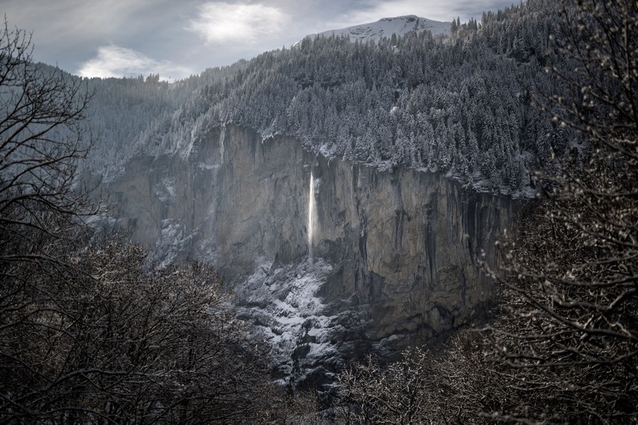 A view of a high-alpine waterfall along a cliff on a cold winter day
