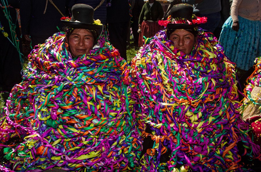 Two people sit side by side, thickly covered in colorful decorations.