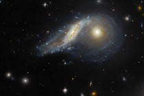 A telescopic view of two colliding spiral galaxies, with one tilted and slightly warped