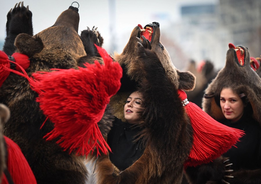 People parade while wearing large bearskins.