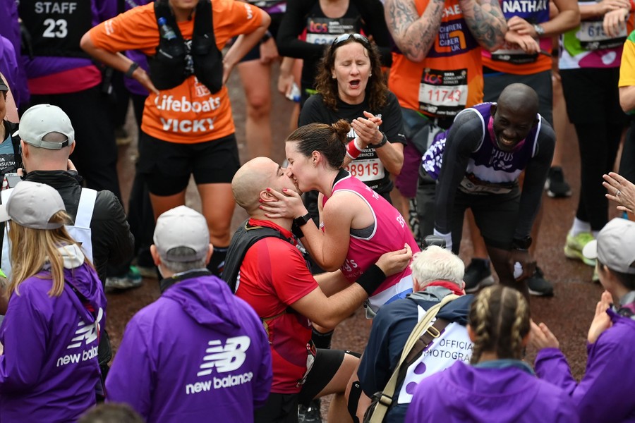 A couple embrace after a proposal on the finish line of a race.