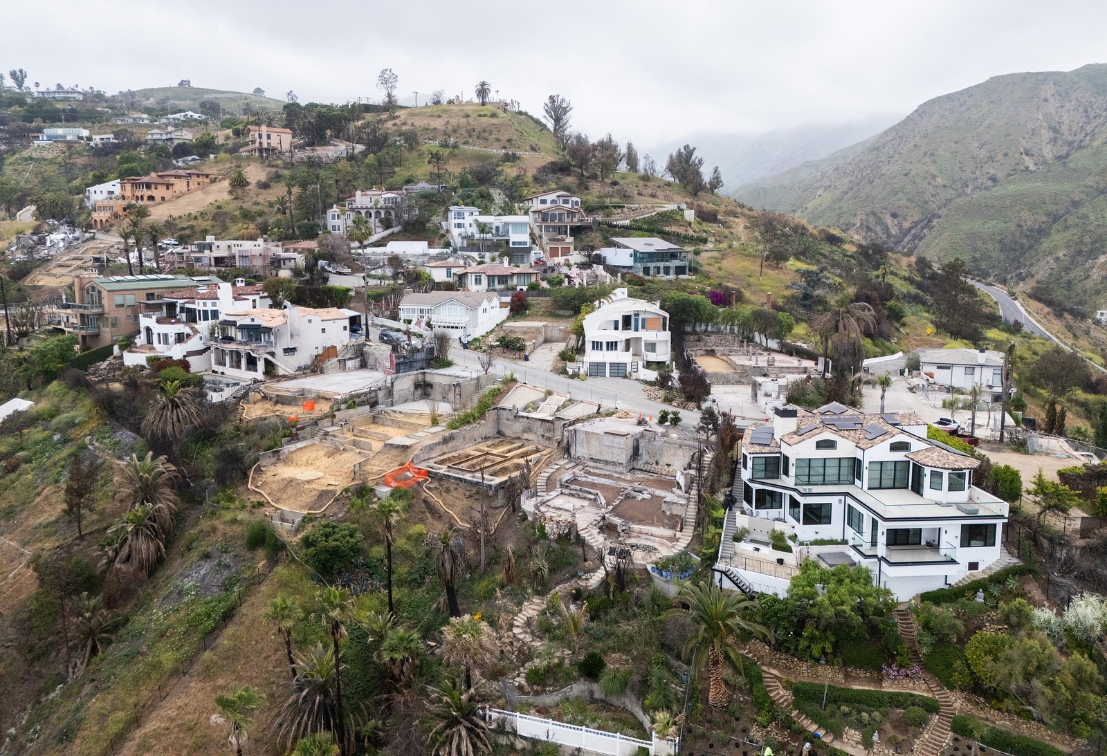 A hillside neighborhood, with several lots cleared after fire damage.