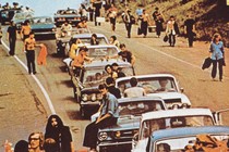 Concertgoers at Woodstock pile outside in cars.