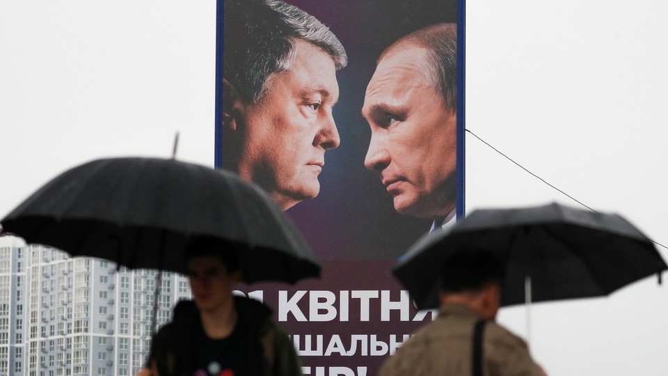 People walk past a campaign billboard, showing Poroshenko and Putin, in Kyiv.