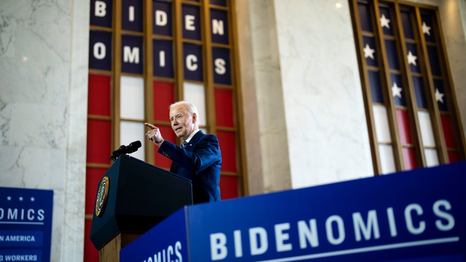Joe Biden speaking above a "Bidenomics" sign