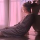 A young woman sitting on the ground staring out the window in "The Pink Cloud"
