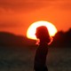 A girl stands in front of a setting sun