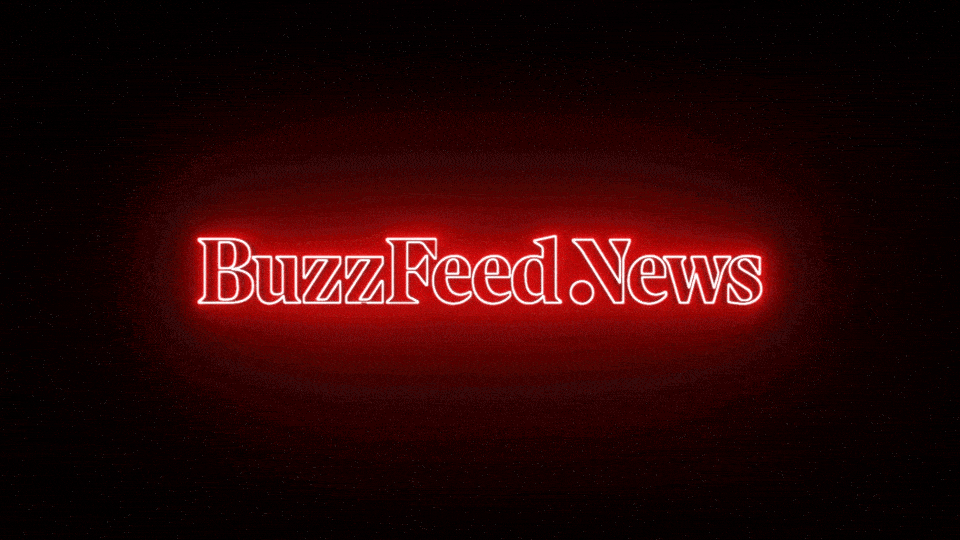 A neon sign reading 'BuzzFeed.News' flickers red against a black background