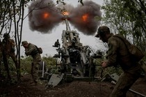 Three soldiers operate a piece of field artillery, firing a shell and causing smoke and fire to erupt from the muzzle.