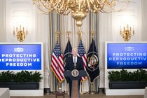 President Joe Biden in a room flanked by two screens that read: Protecting reproductive freedom