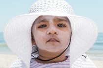 A child in a white hat with lots of sunscreen on her face