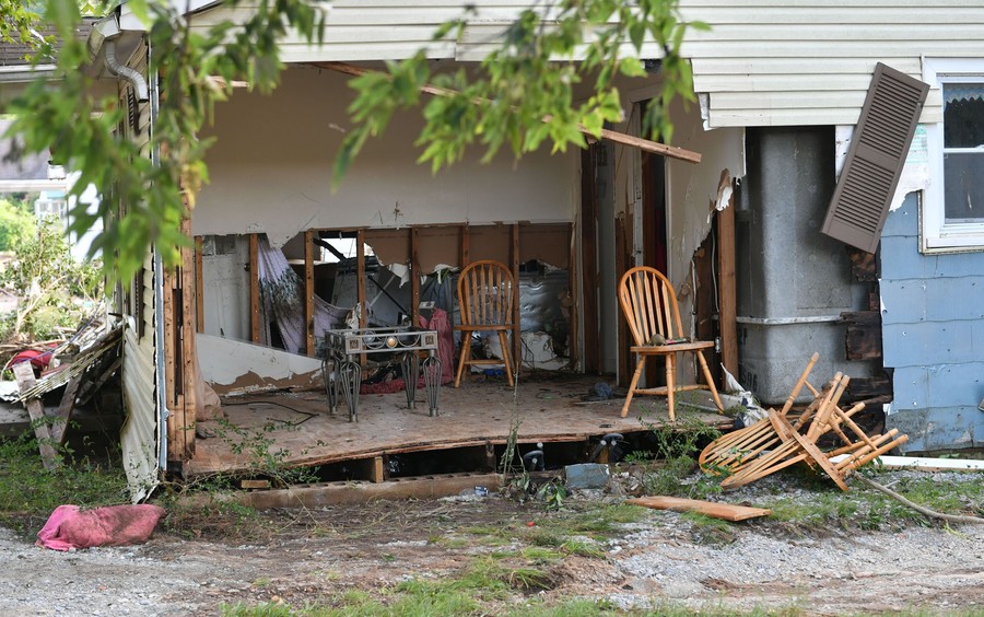Chairs and debris are seen inside a room of a flood-damaged house.